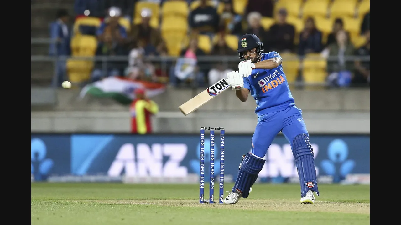 Photograph of an India batsman playing a shot with the stumps behind him in a night match