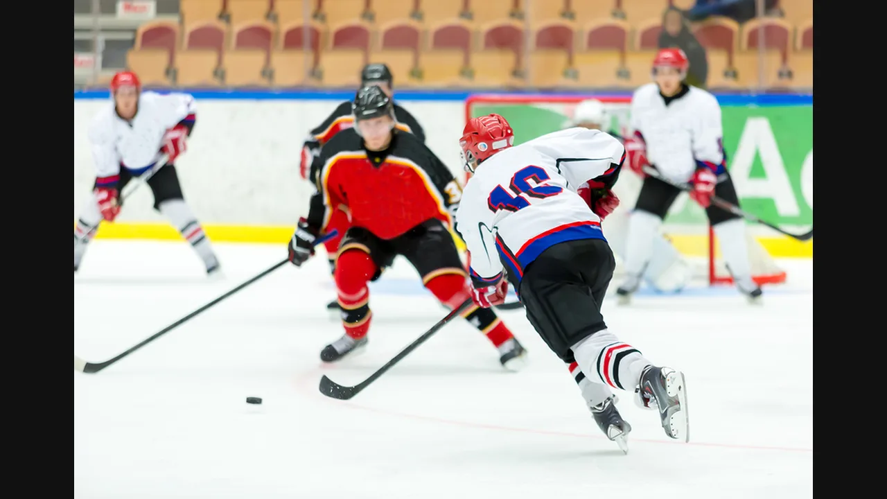 Photograph of ice hockey players chasing the puck across the rink during a game